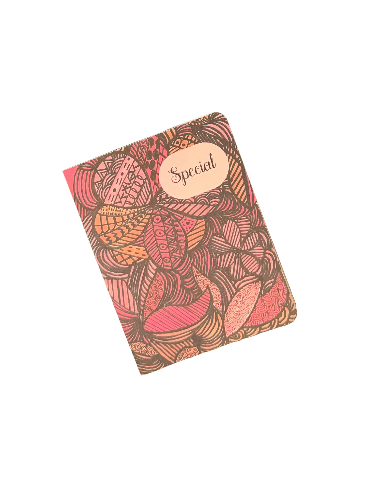 A square notebook or journal with a detailed botanical pattern in pink, orange, and brown, featuring a beige label that reads 'Special', placed on a wooden surface.